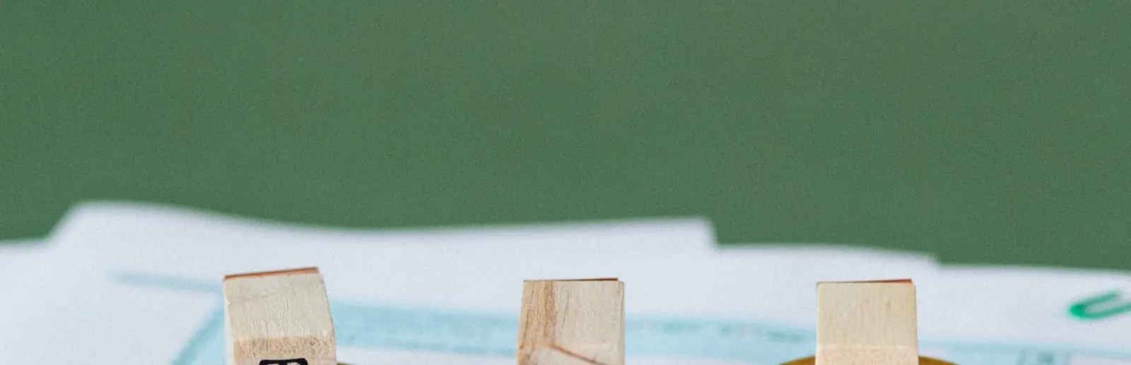 Wooden blocks spelling TAX on stacked coins over tax forms, illustrating property tax rates