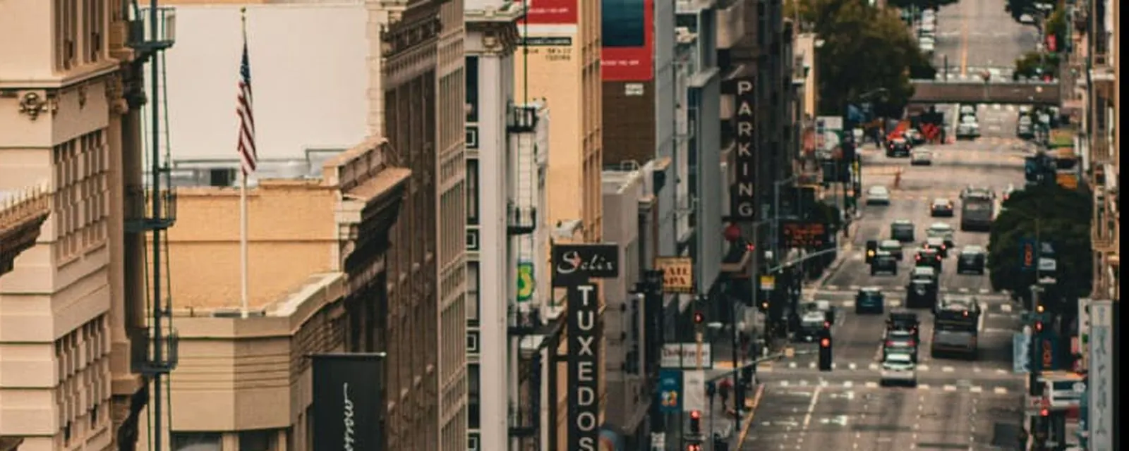 Downtown city street seen from above, lined with storefronts and traffic