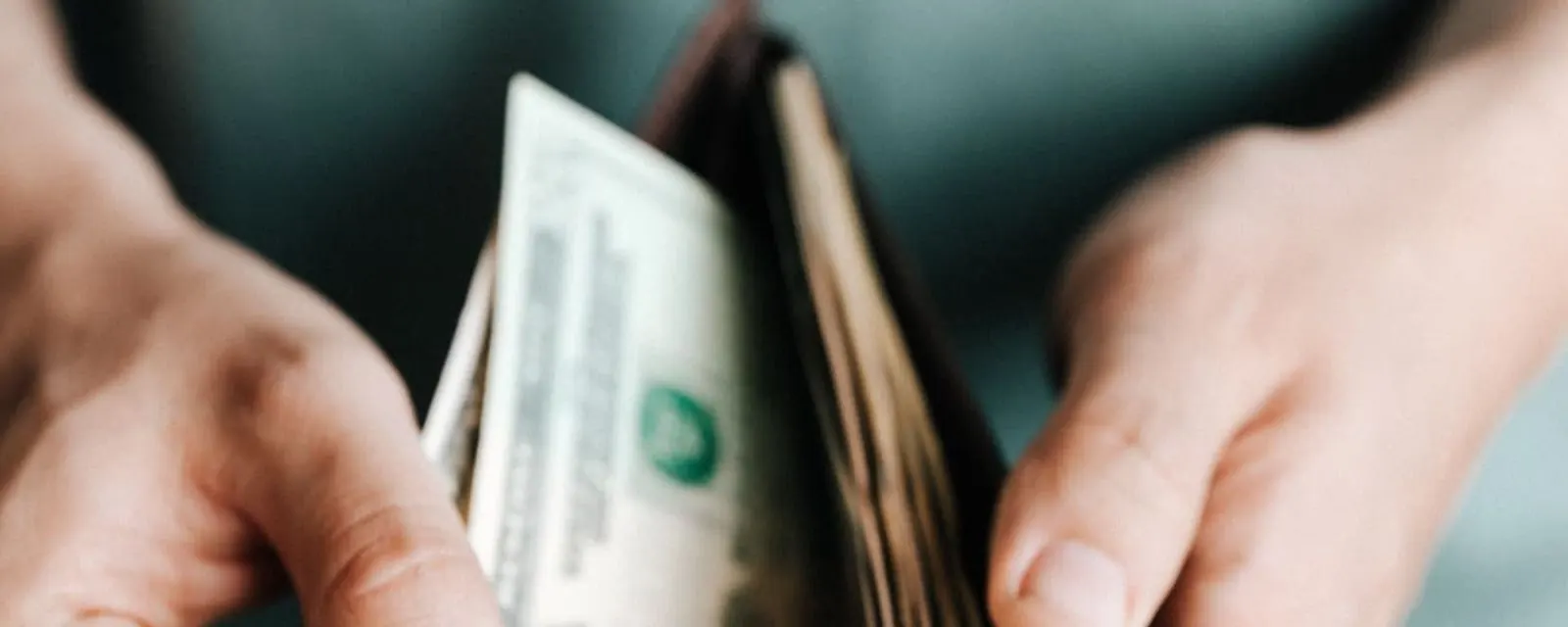 Hands counting dollar bills from a wallet, illustrating the salary and paycheck tool