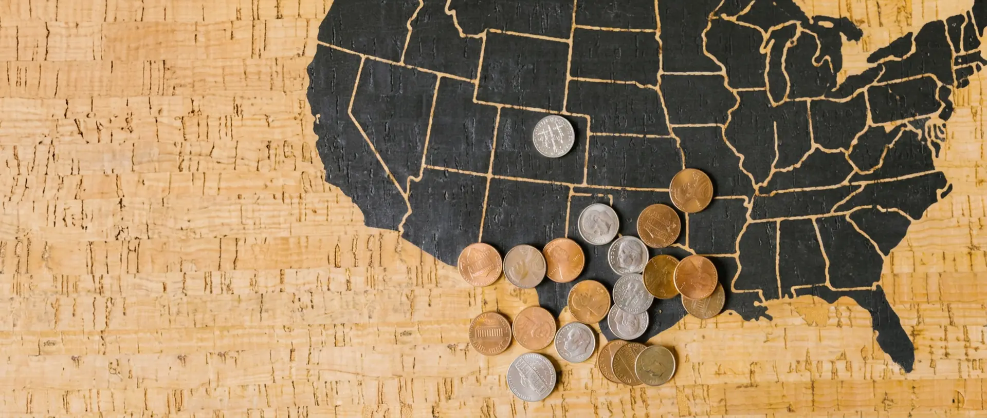 Cork map of the United States with US coins scattered across it, representing local sales tax and ZIP code data