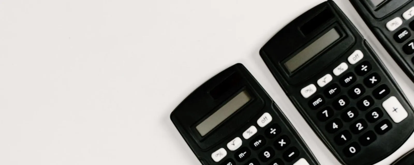 Row of pocket calculators on a white desk, illustrating the tools hub