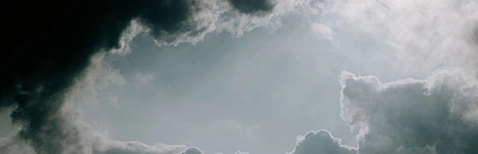 Break of blue sky framed by towering storm clouds above a US weather data page